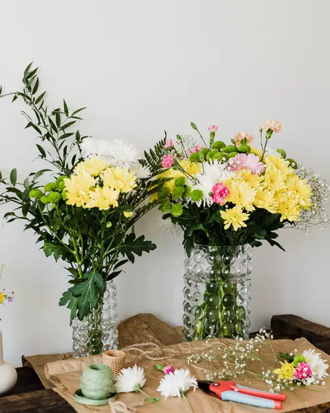 Bouquets de chrysanthèmes jaunes et blancs dans des vases en verre